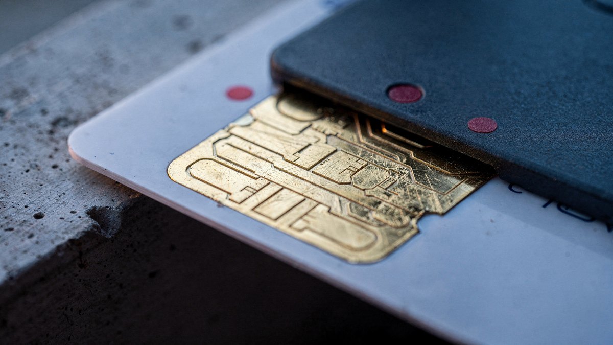 Extreme macro photograph of gold microchip contacts on a smartcard inserted into a reader under cool twilight light.